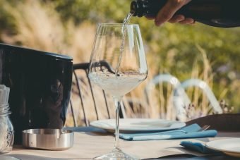 male-hand-pouring-alcoholic-beverage-elegant-glass-table-openair-event male-hand-pouring-alcoholic-beverage-elegant-glass-table-openair-event